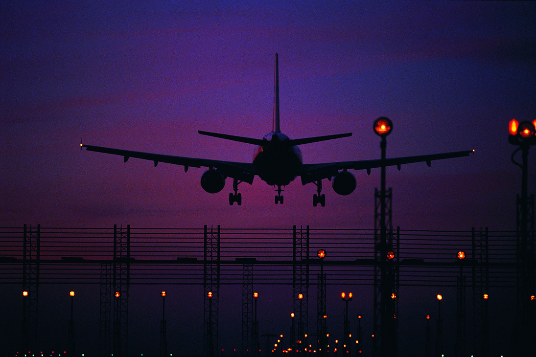 Silhouetted plane landing at night